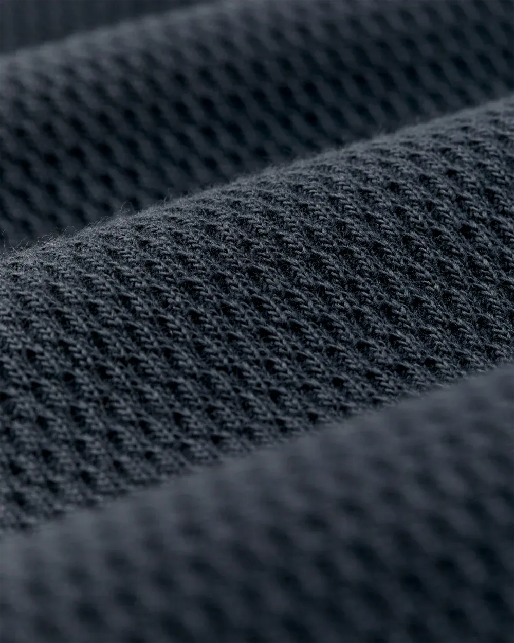Close-up of a dark charcoal gray knit fabric texture with a fine mesh-like weave.
