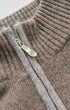 Close-up of a ribbed knit sweater with a silver zipper and pull tab, showing the texture and color of the fabric in detail.