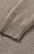Close-up of a ribbed knit sweater cuff in a warm taupe-beige color, showing the texture and stitching detail.
