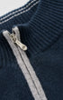 Close-up of a navy blue ribbed knit sweater with a silver zipper and a light gray stripe running down the front.
