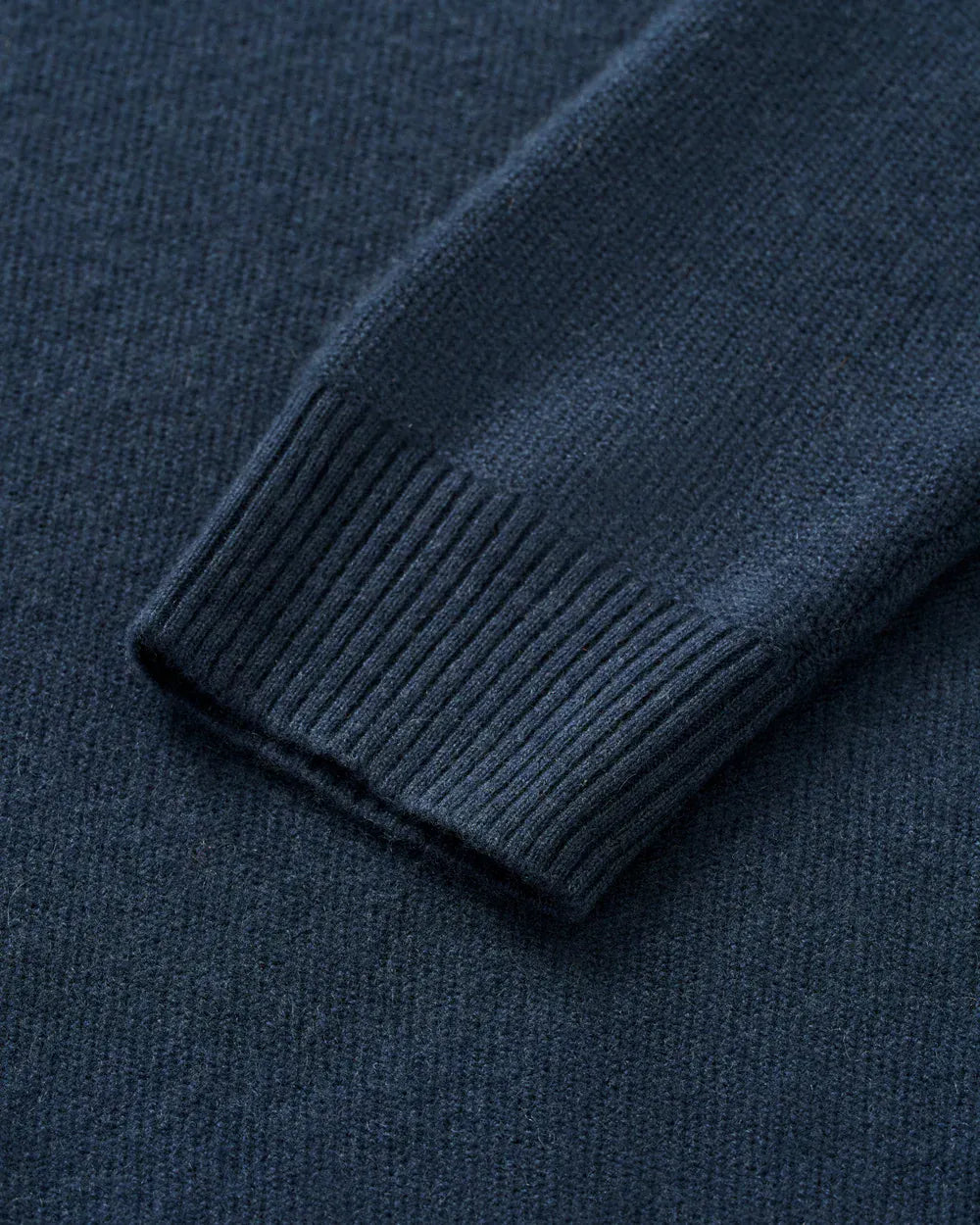 Close-up of a dark navy blue knit fabric with a ribbed cuff detail.