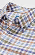 A close-up of a men's long-sleeve button-down shirt featuring a multi-colored checkered pattern in blue, green, brown, and white.