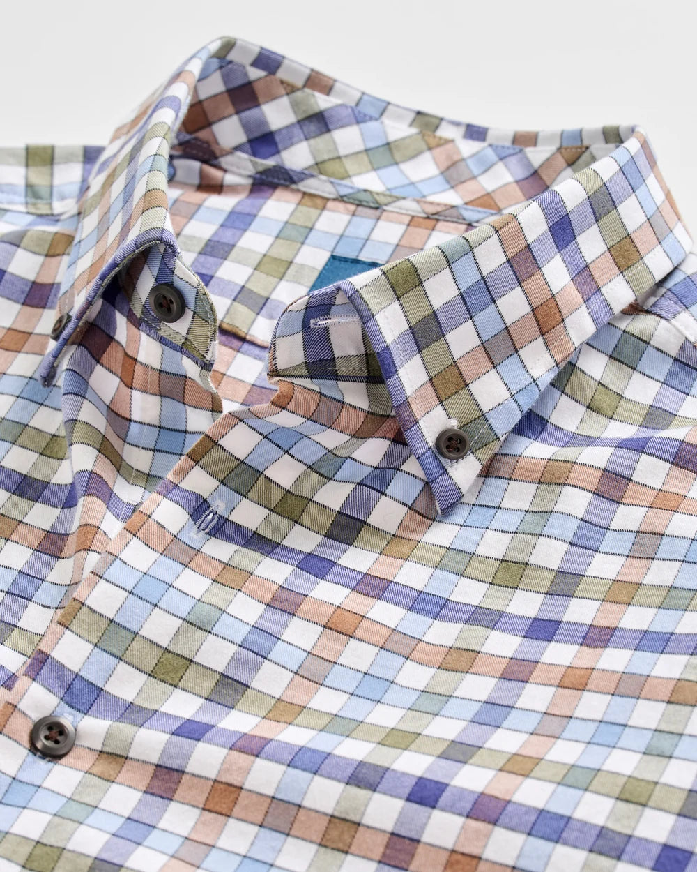 A close-up of a men's long-sleeve button-down shirt featuring a multi-colored checkered pattern in blue, green, brown, and white.