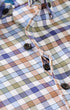 Close-up of a plaid button-up shirt with a multicolor check pattern in blue, purple, beige, and brown tones, featuring black buttons.