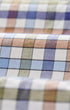 A close-up of folded plaid fabric with a multicolor check pattern featuring white, blue, purple, beige, and brown tones.