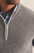 Close-up of a man wearing a light gray ribbed knit quarter-zip sweater over a blue and white checkered collared shirt.