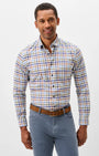 A man wearing a long-sleeve button-down shirt with a multicolor plaid pattern in blue, orange, and white, paired with blue jeans and a brown belt, against a plain light gray background.