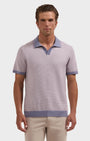 A man wearing a short-sleeve knit polo shirt in a light lavender-gray color with contrasting dusty blue trim on the collar, sleeve cuffs, and hem, paired with beige trousers, against a solid light gray background.