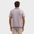 A man viewed from the back wearing a light lavender knit polo shirt with contrasting dusty purple trim on the collar, sleeve cuffs, and hem, paired with beige trousers, against a solid light gray background.