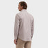 A man shown from the back wearing a light beige and white micro-patterned long-sleeve button-down shirt and khaki pants, against a solid light gray background.