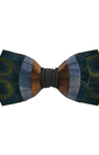 A men's self-tie bow tie featuring a multi-colored patchwork design with peacock-feather-inspired circular motifs in blue, green, and gold, accented by vertical stripes of brown, orange, and gray, finished with a dark gray elastic band.
